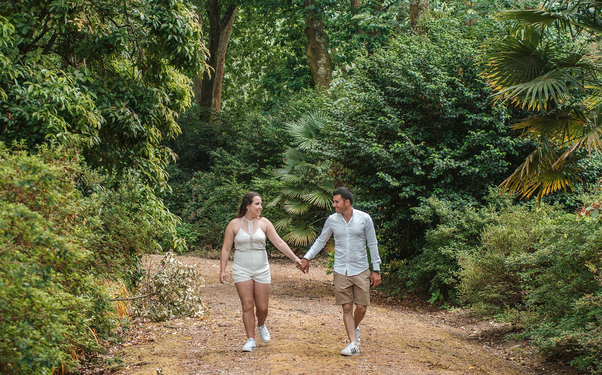 Casal a olhar um para o outro enquanto caminham de m&atilde;os dadas