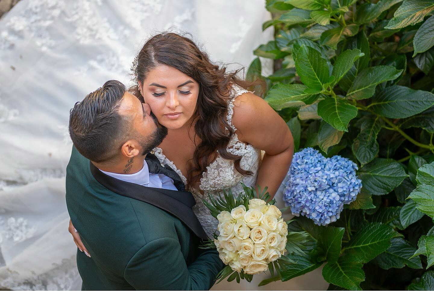 Noivos no dia do casmento com noivo a dar beijo na face