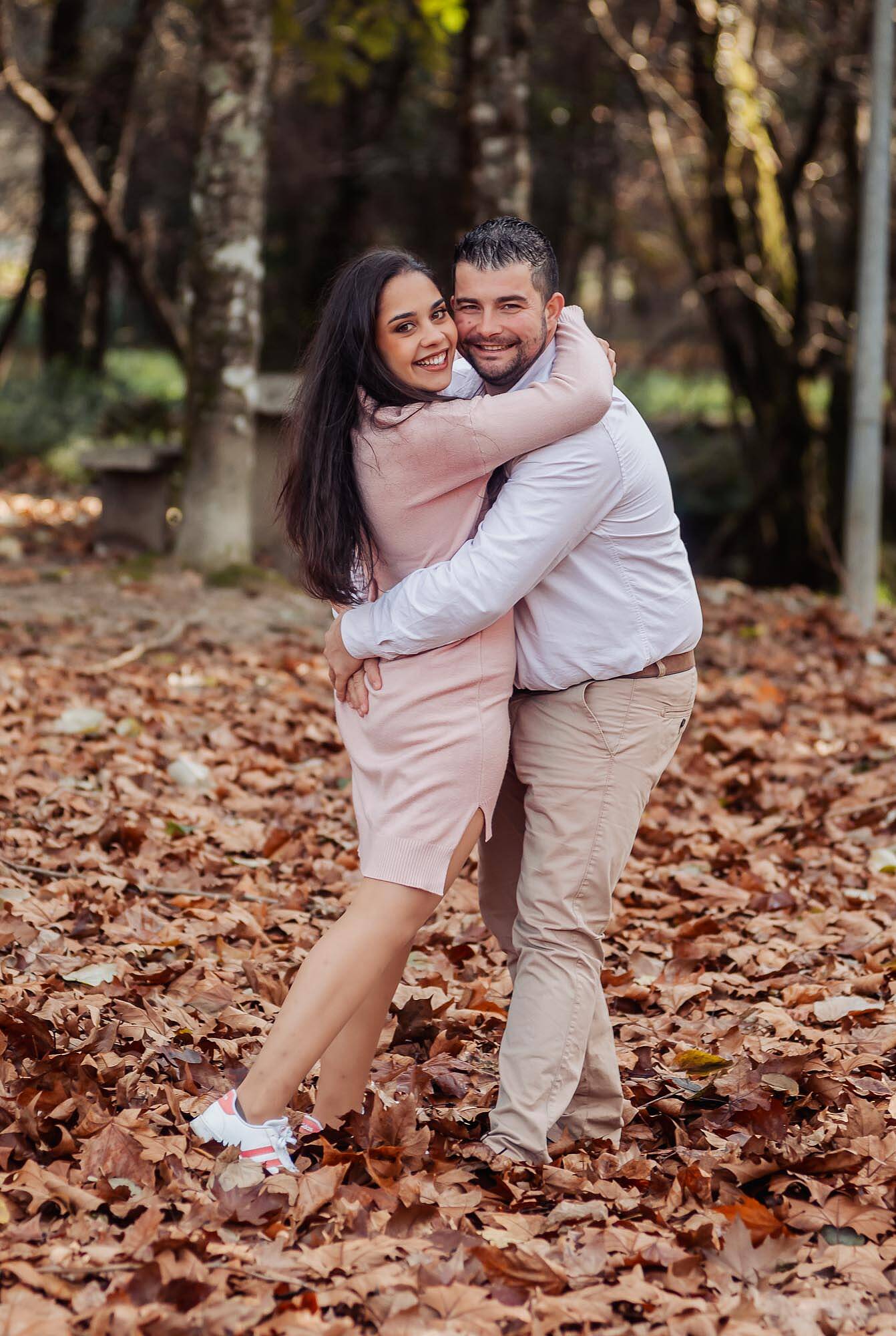 abraçados no meios das folhas a olhar para o fotografo