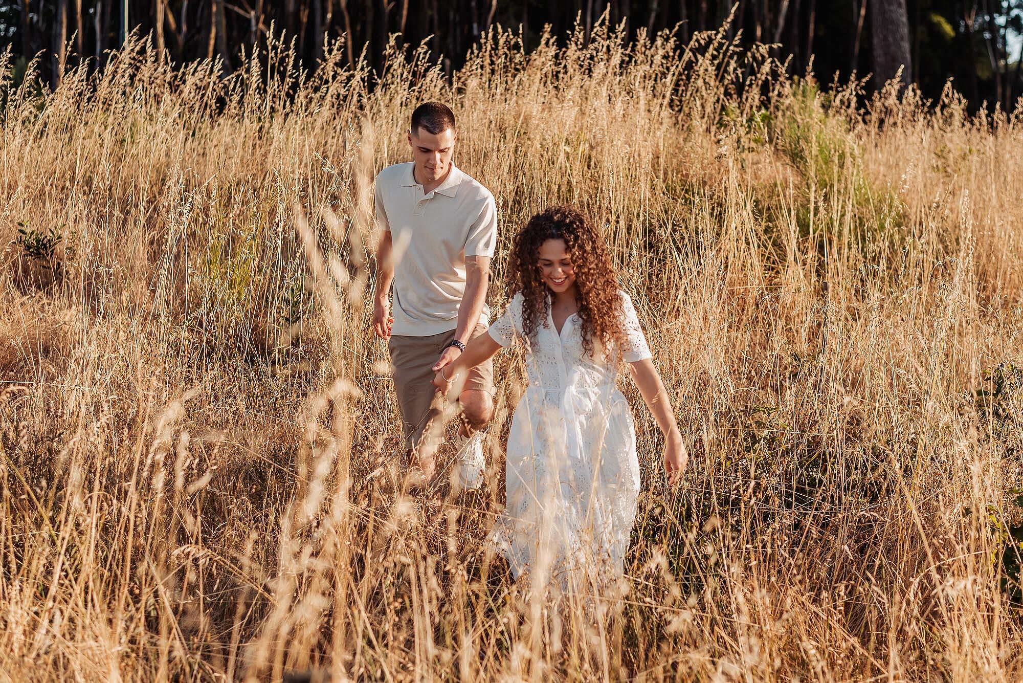 casal a caminhar de maos dadas pelo meio do campo seco
