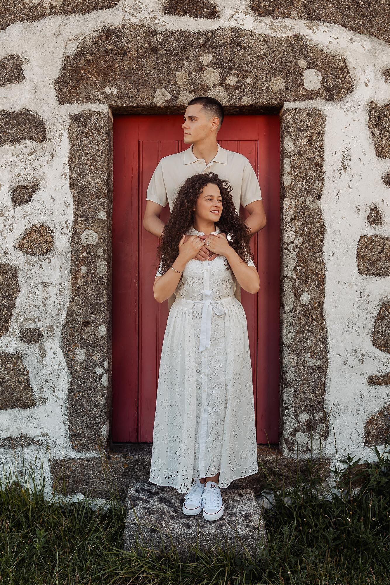 casal abracado em frente a uma porta vermelha antiga de pedra
