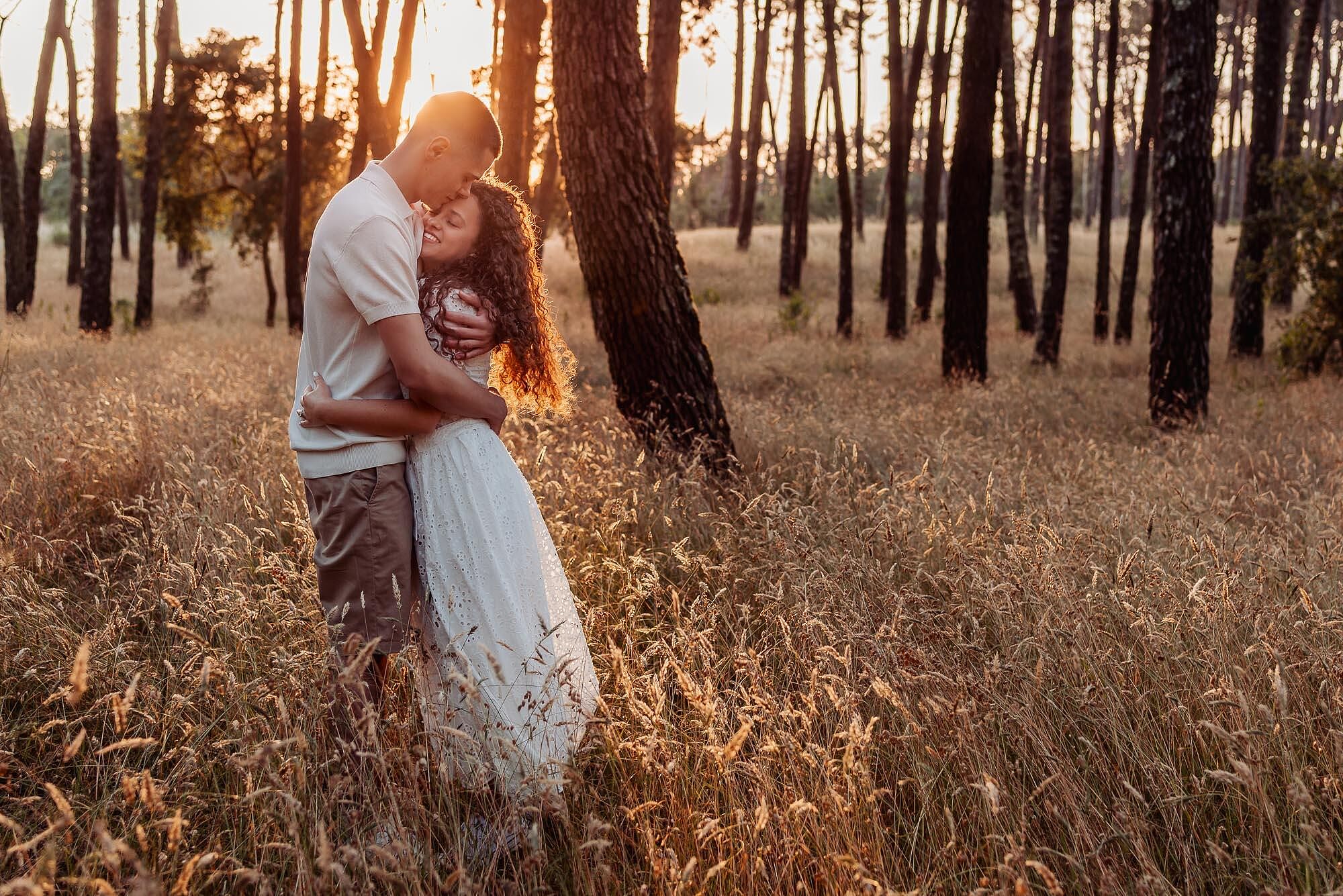 casal abracado no campo iluminado pela luz dourada do entardecer