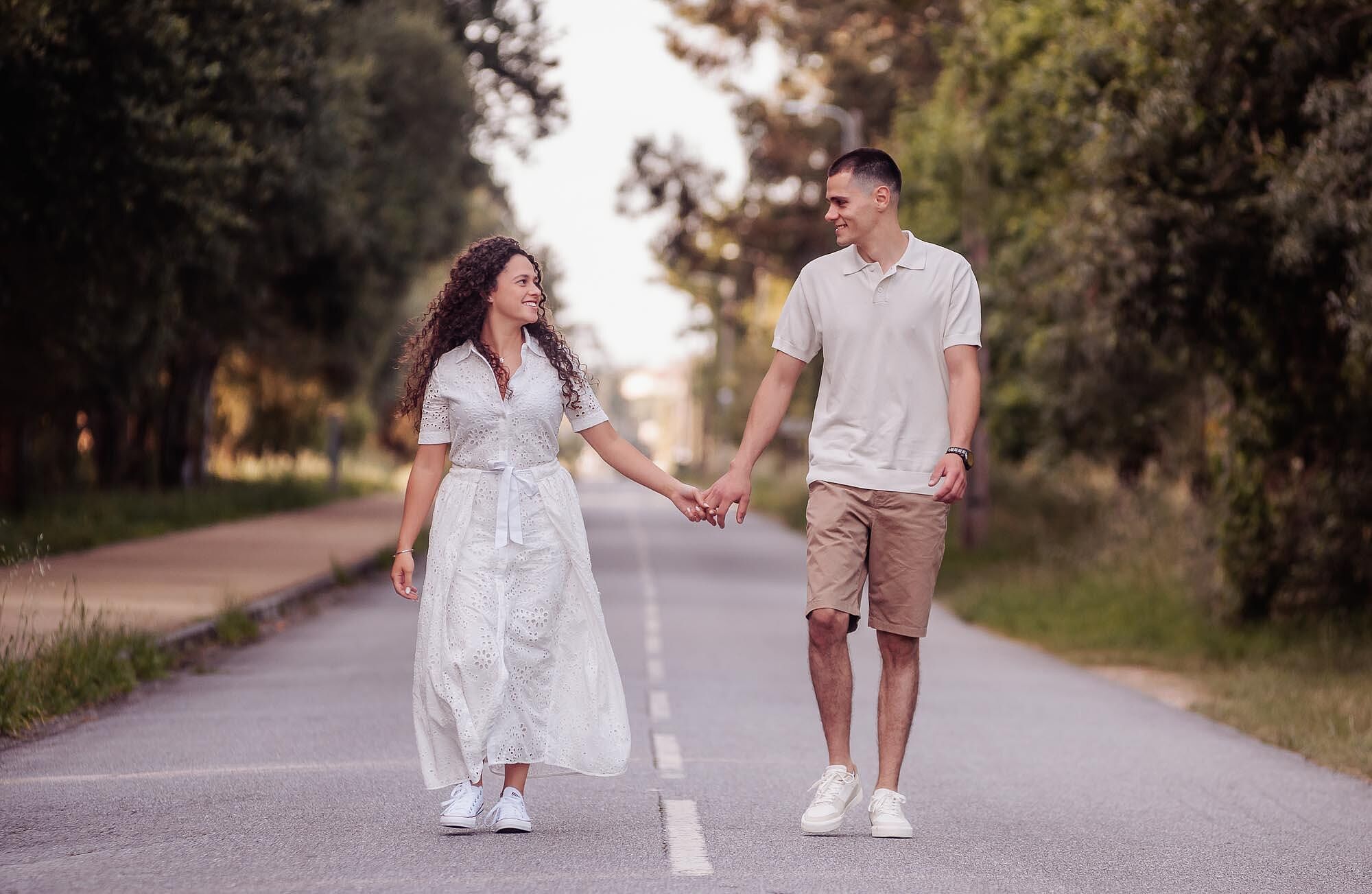 casal de maos dadas a caminhar no meio da estrada