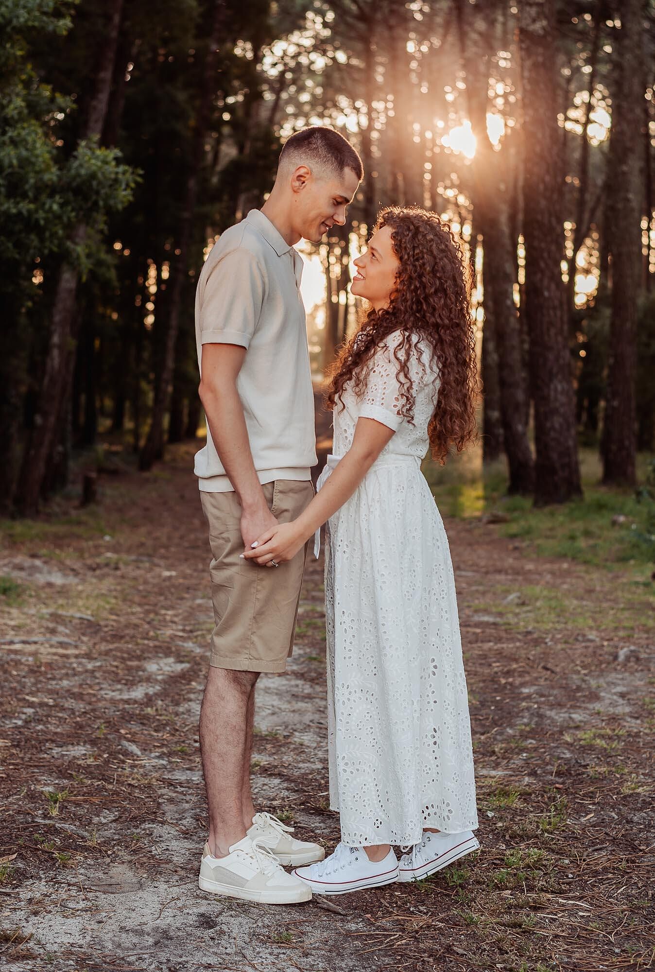 casal de maos dadas a sorrir na floresta ao entardecer