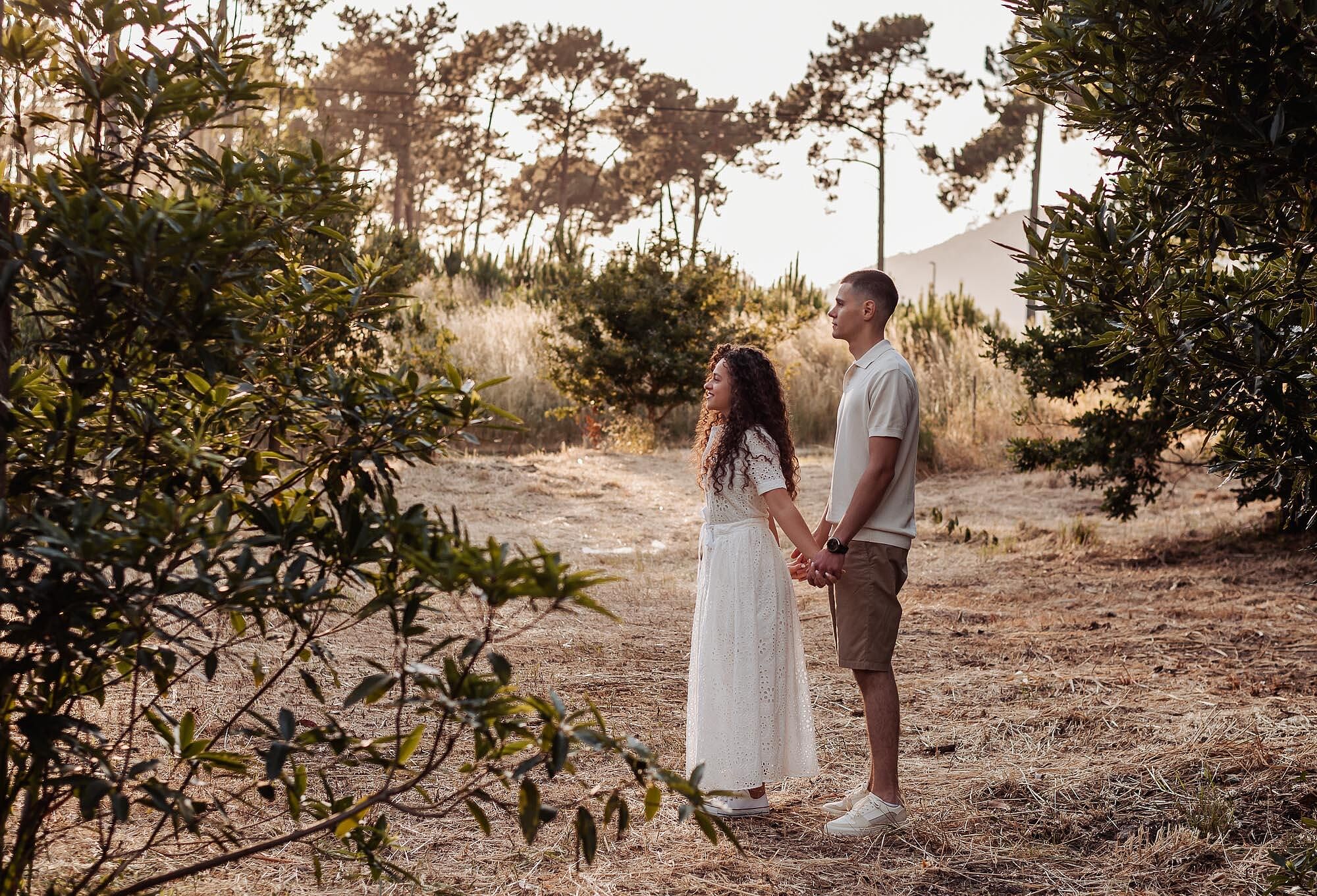 casal de maos dadas em clareira rodeada de arvores