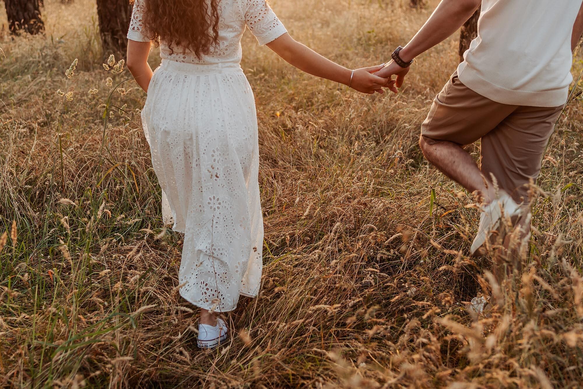 detalhe de casal a caminhar de maos dadas visto por tras