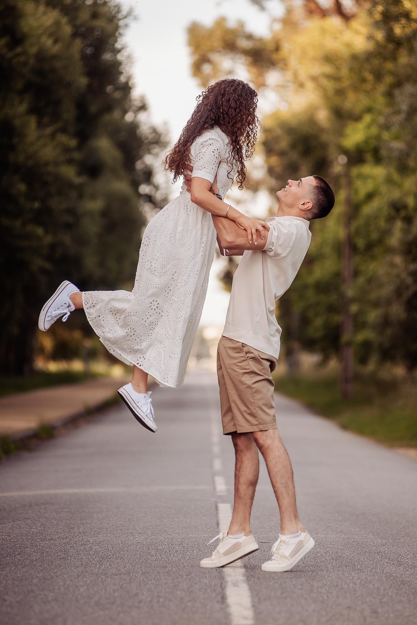 homem levanta a mulher nos bracos com alegria no meio da estrada