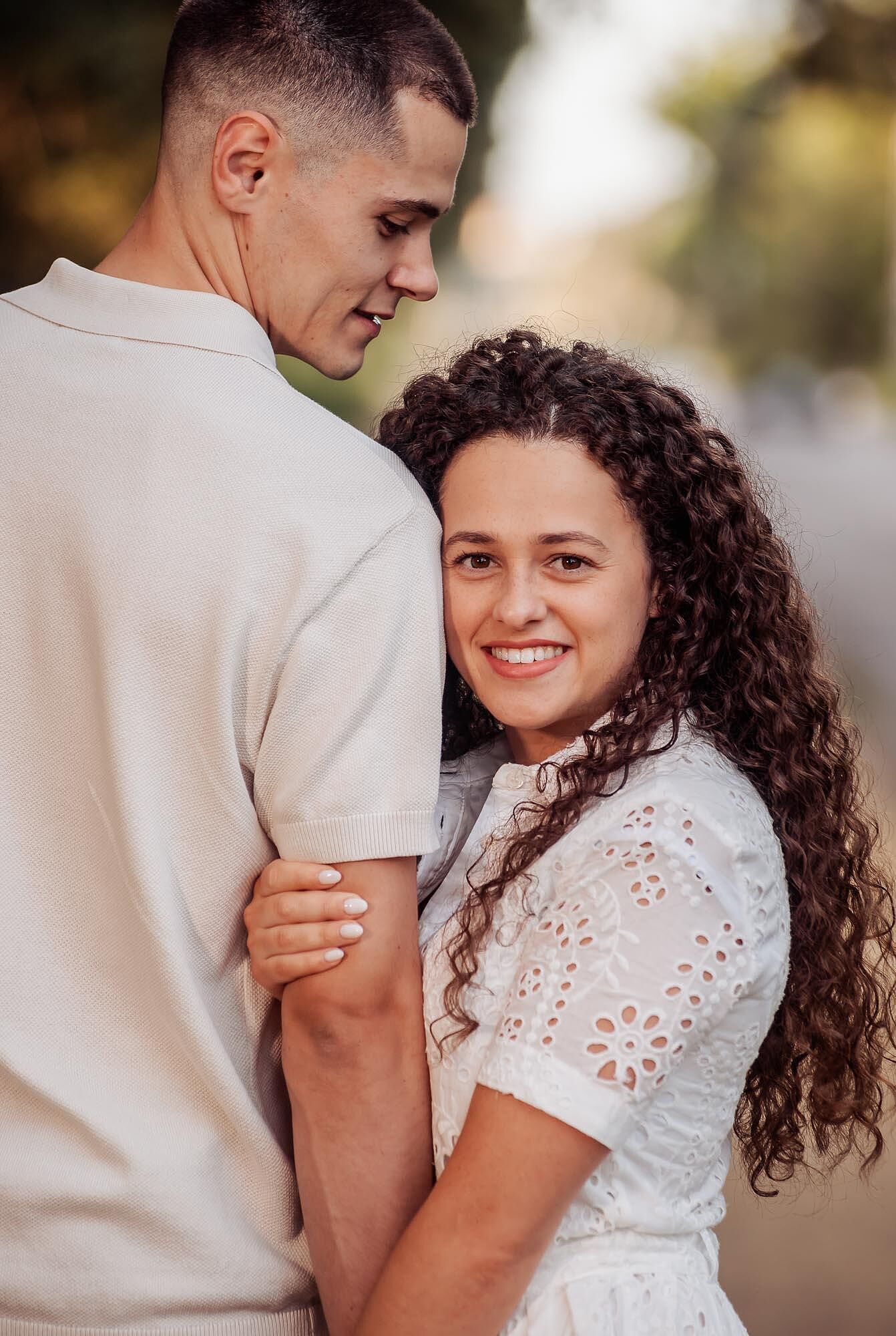 mulher abraca o braco do companheiro e olha para a câmara a sorrir