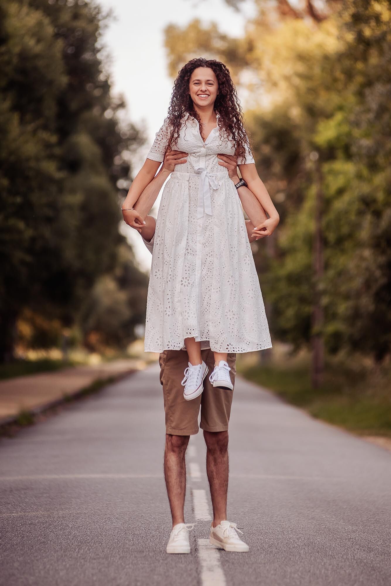mulher sentada sobre os ombros do homem a sorrir na estrada