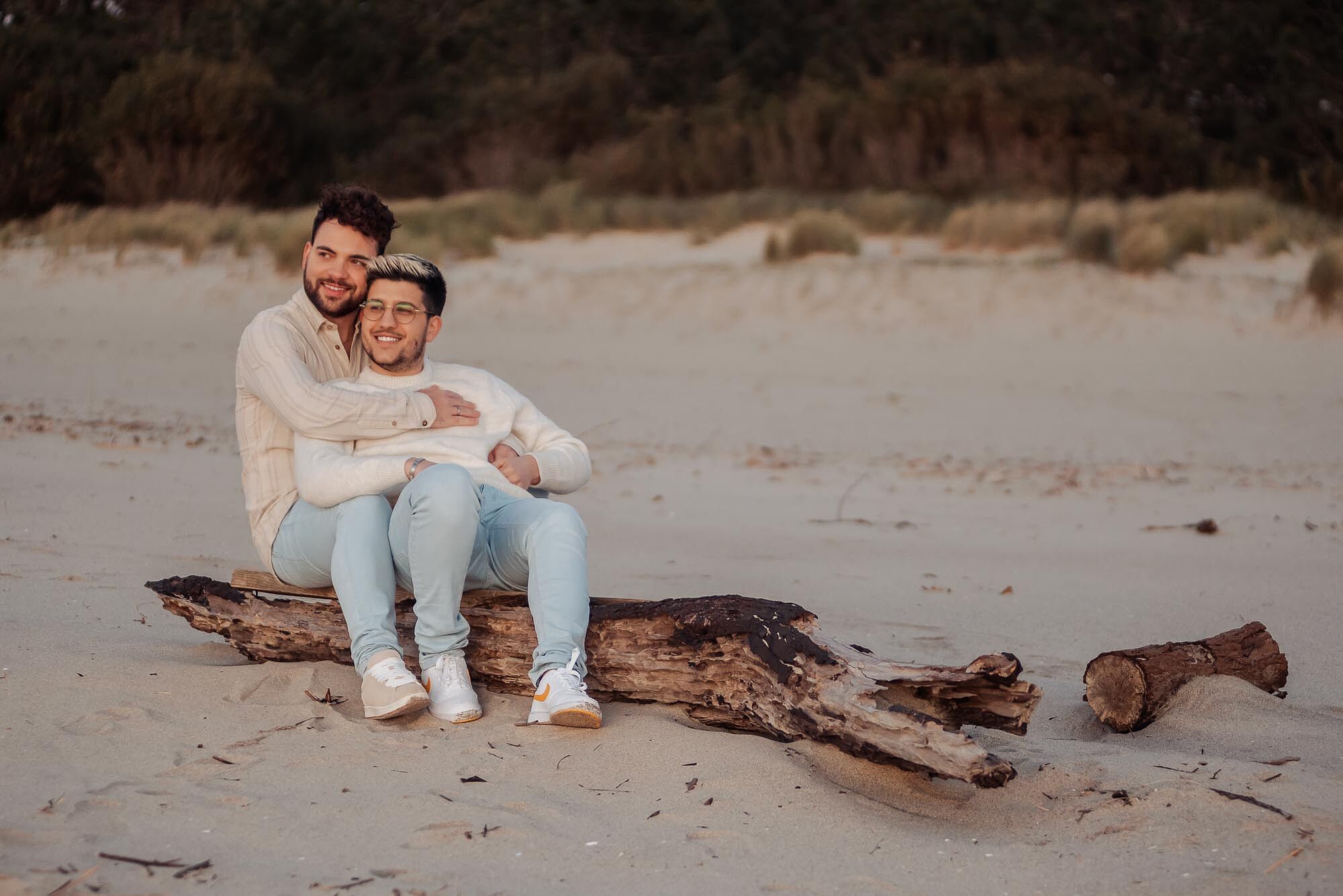 namorados na praia sentados em tronco que deu á costa