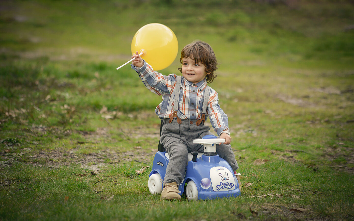 Boy riding a toy car with a balloon in his hand