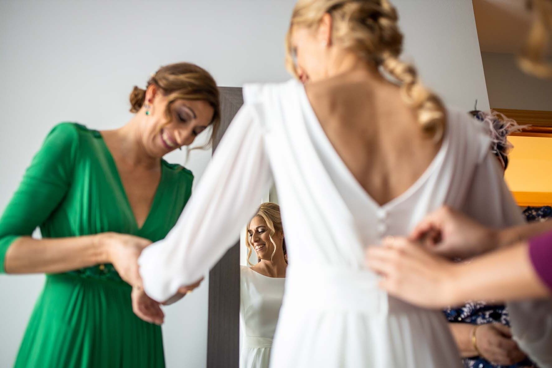 Raquel comenzando a vestirse el día de su boda en su casa junto a su familia.