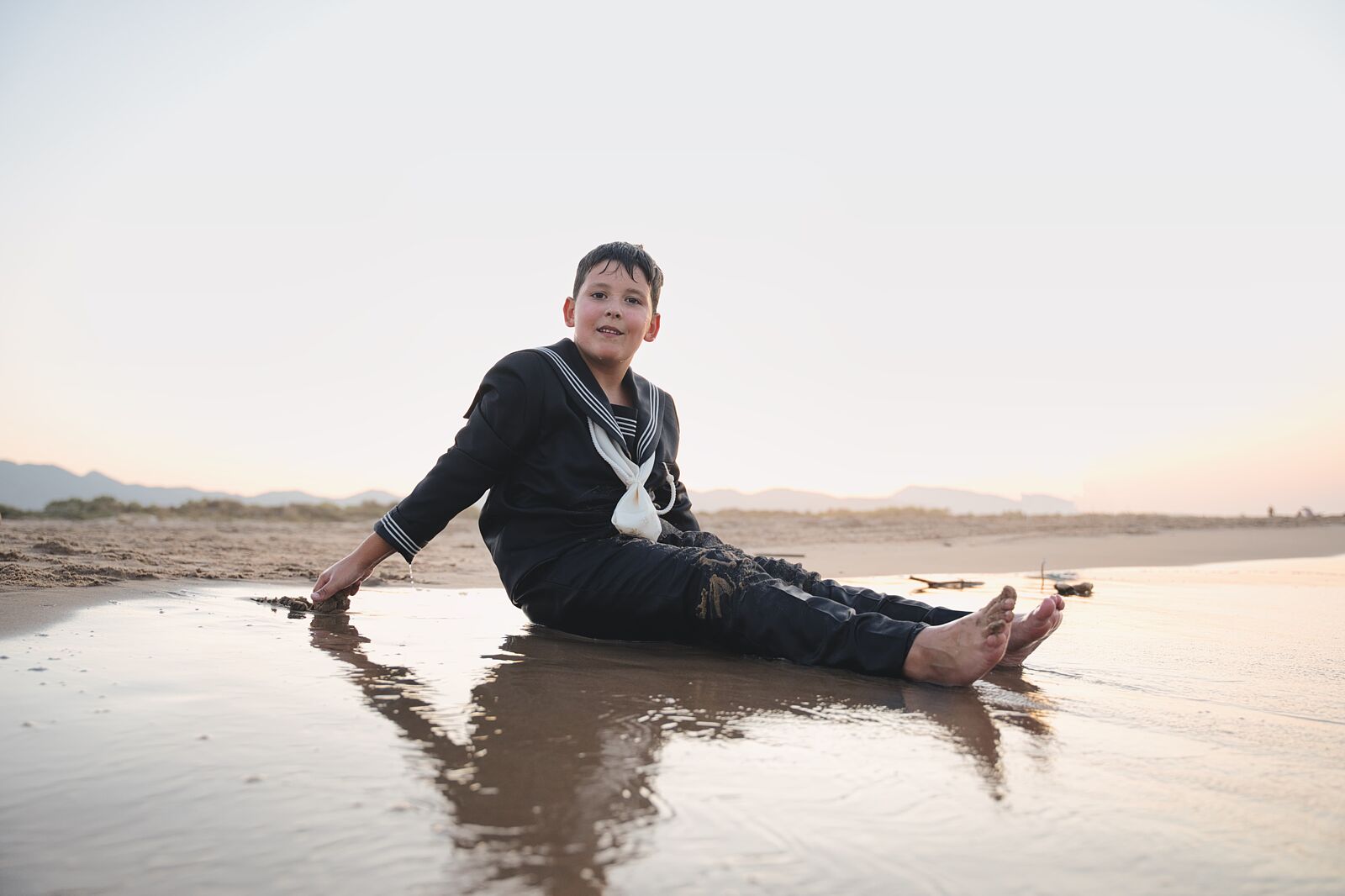 Niño sentado en la arena mojada junto al mar en la playa de Gandía