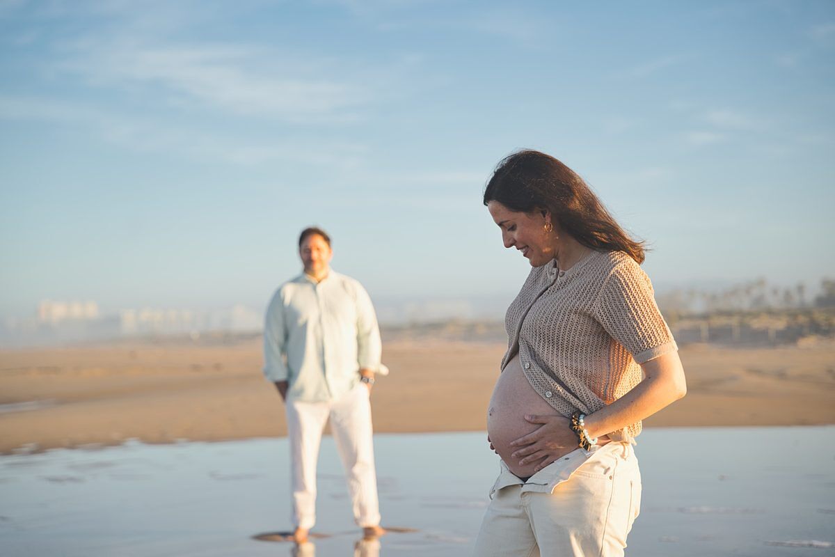 Embarazada mirando su barriga en la playa de Xeraco al atardecer - fotógrafo embarazo Gandía Safor Juan Reig