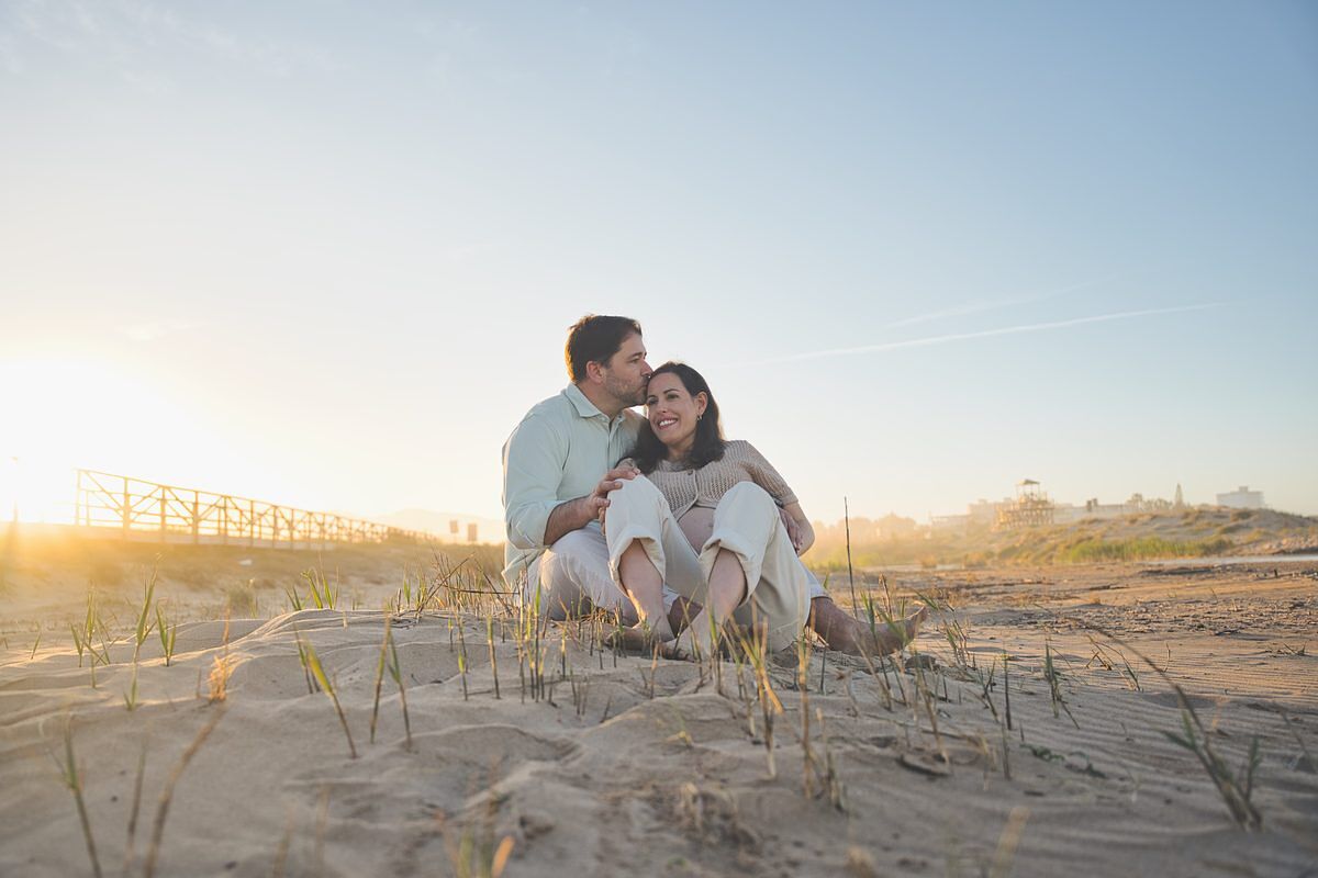 Beso en las dunas de la playa de Xeraco al atardecer - fotografía embarazo natural Gandía