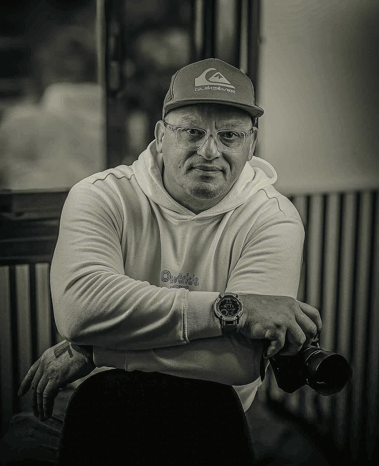 Autorretrato de Laurentiu Pandele fotógrafo de Odinfoto Retrato artístico en blanco y negro de un hombre con gafas y rosario, posando con la mano cerca del rostro sobre un fondo oscuro
