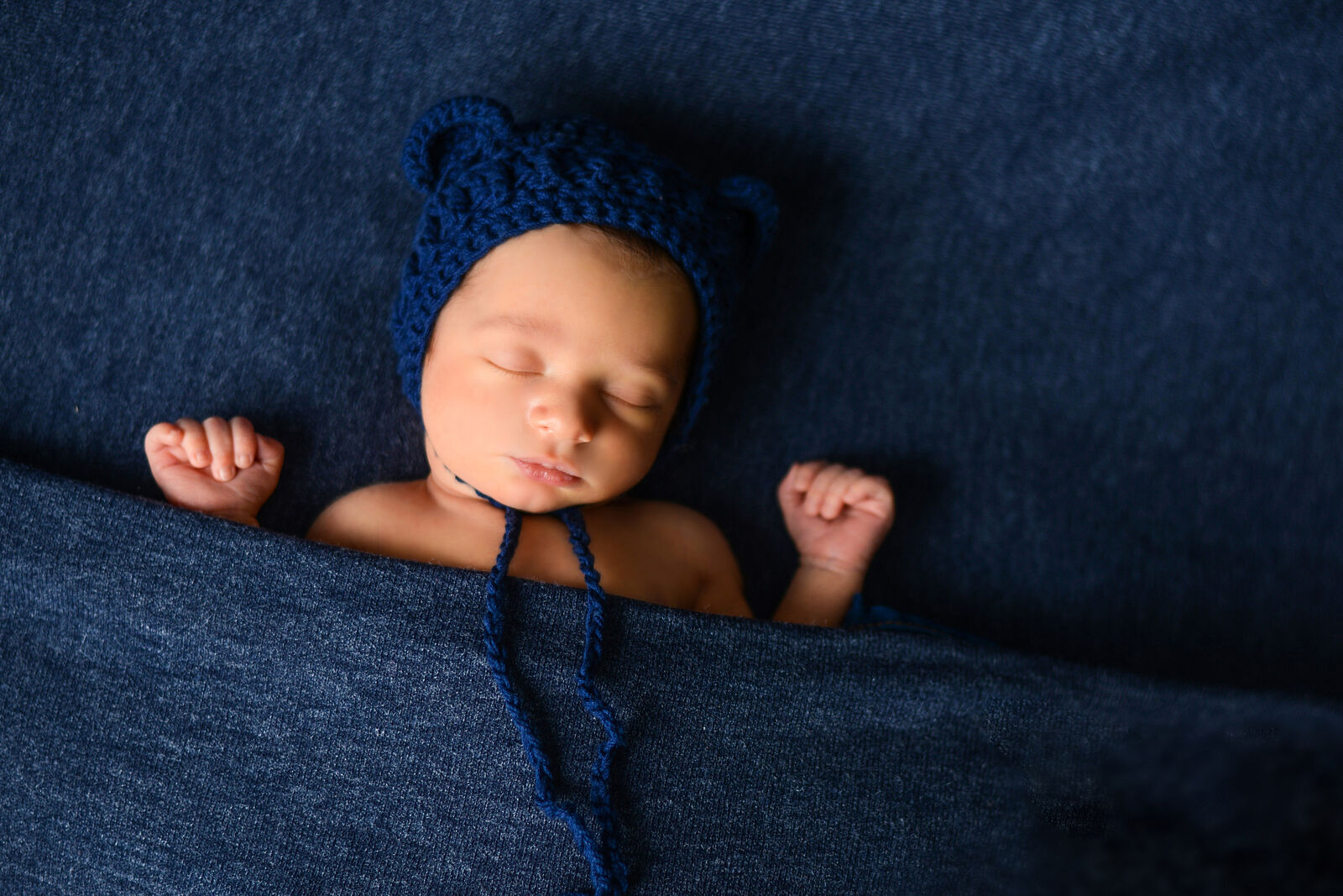 Bebé recién nacido dormido con atrezzo artesanal, fotografía newborn profesional en Madrid.