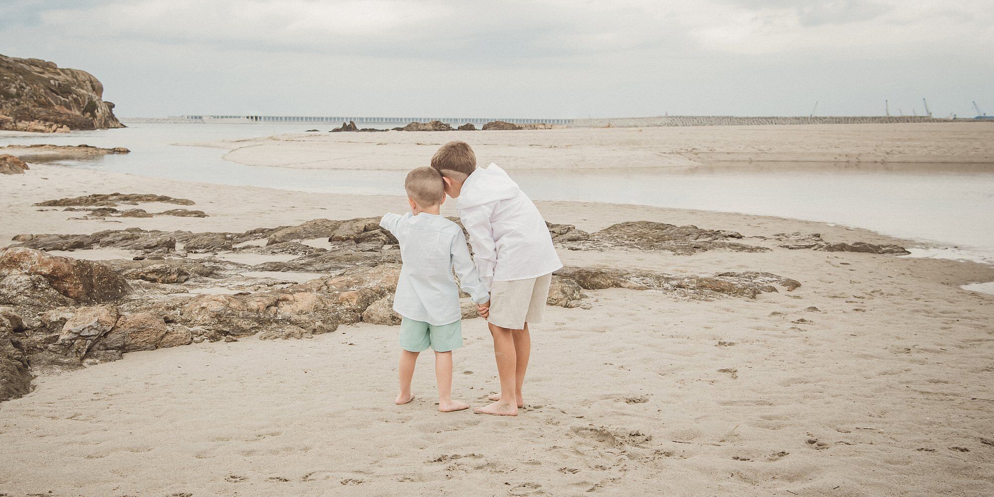 Dos hermanos juegan junto al mar durante una sesión familiar