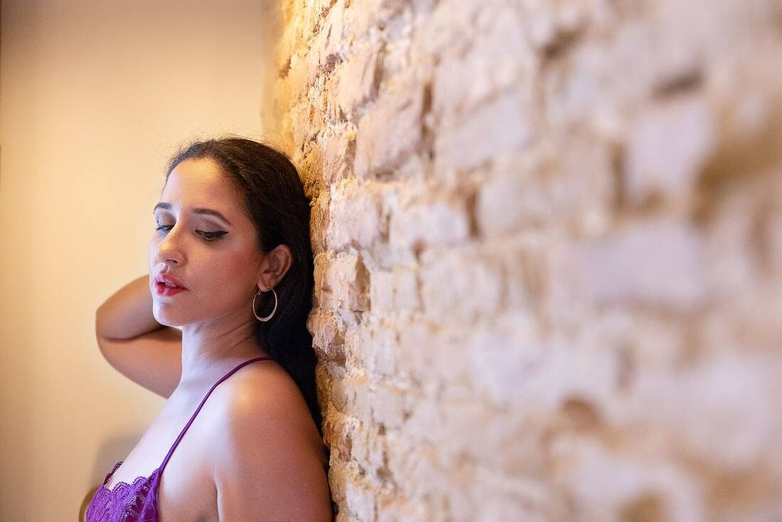Retrato boudoir junto a pared de ladrillo con luz cálida